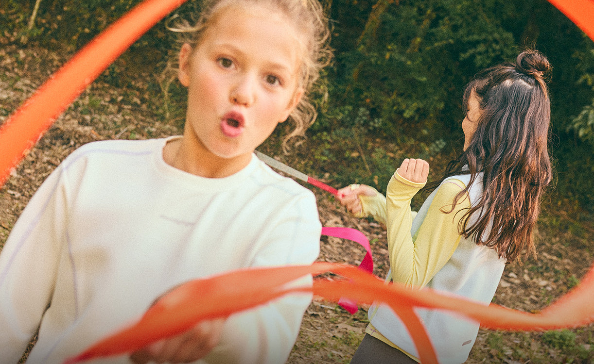 Two children playing with ribbons in a natural setting