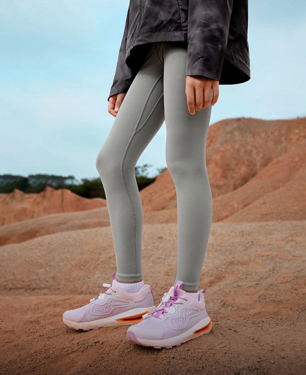 Person wearing light gray leggings and pink athletic shoes in a desert-like setting