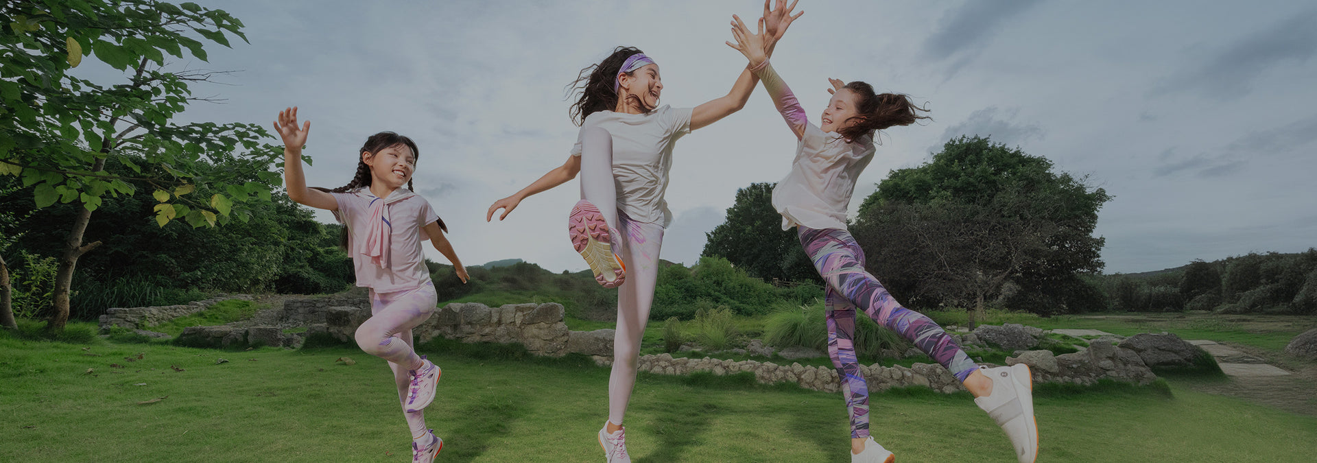 moodytiger two young girls wearing colourful leggings by moodytiger jumping in a green outdoor field